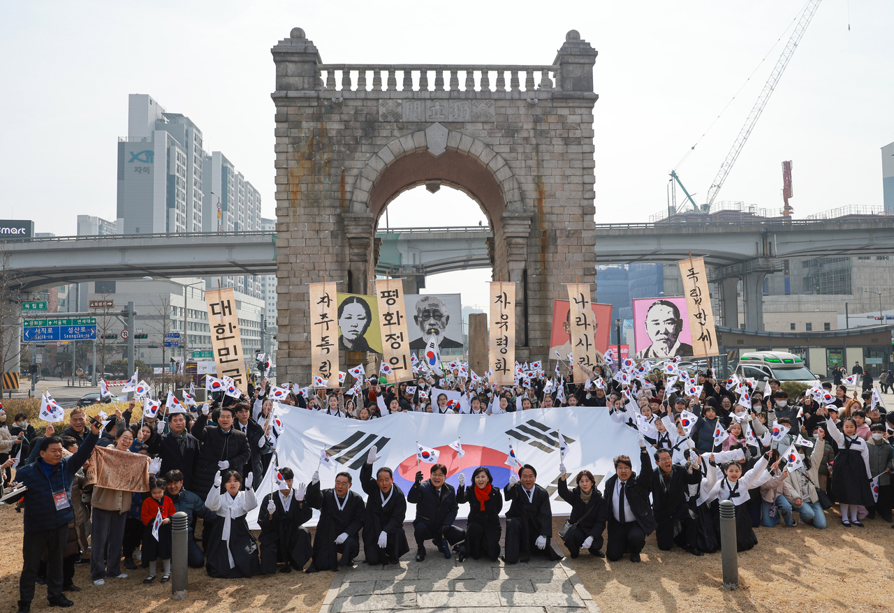 Participants of the 'Seodaemun 1919: Echoes of Freedom' event gather at Dongnimmun Arch in Seoul on Saturday, waving Taegukgi flags and holding banners honoring Korea’s independence activists. (Yonhap)