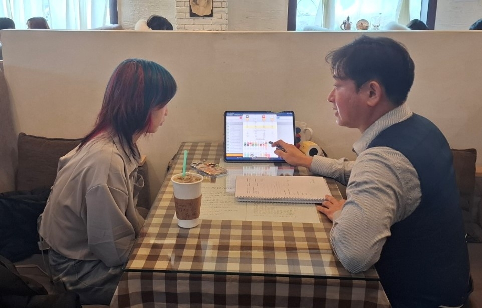 Joy Bunch (left), a 26-year-old American artist, pays close attention in her saju reading session at a saju cafe in Hongdae, Seoul. (Shin Ji-hye/The Korea Herald)