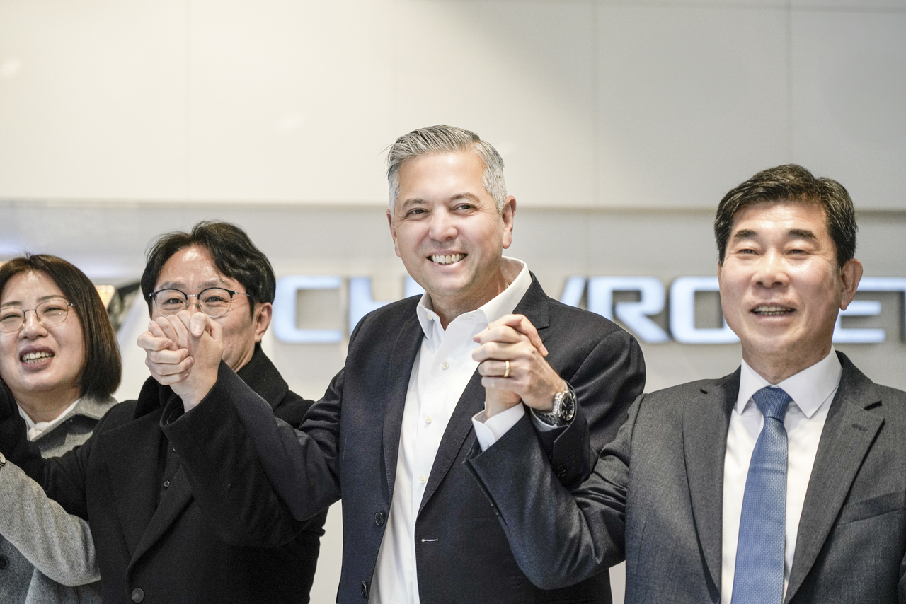 GM Korea President and CEO Hector Villarreal (second from right) holds hands with staff at the Chevrolet Shinchon dealership in Seoul on Friday. (GM Korea)
