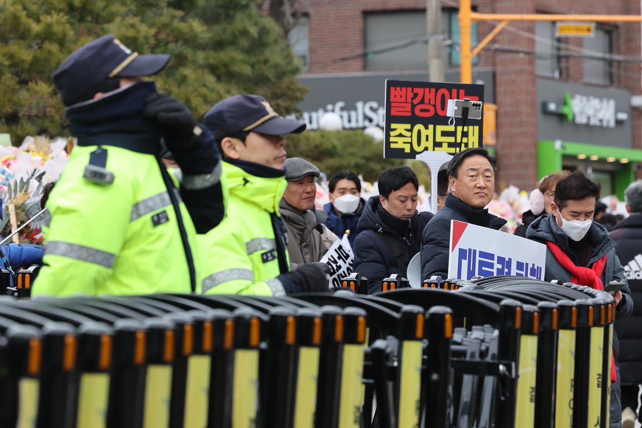 Pro-Yoon protesters protest against President Yoon Suk Yeol’s impeachment next to police officials controlling access at the entrance of the Constitutional Court of Korea in Jongno-gu, central Seoul, Wednesday. (Yonhap)