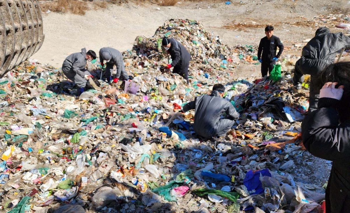 Civil servants from the local sanitation department search through the garbage at an area central waste processing station to help a woman find 26 million won she had accidentally thrown away in Sejong City, Feb. 24. (Sejong City)