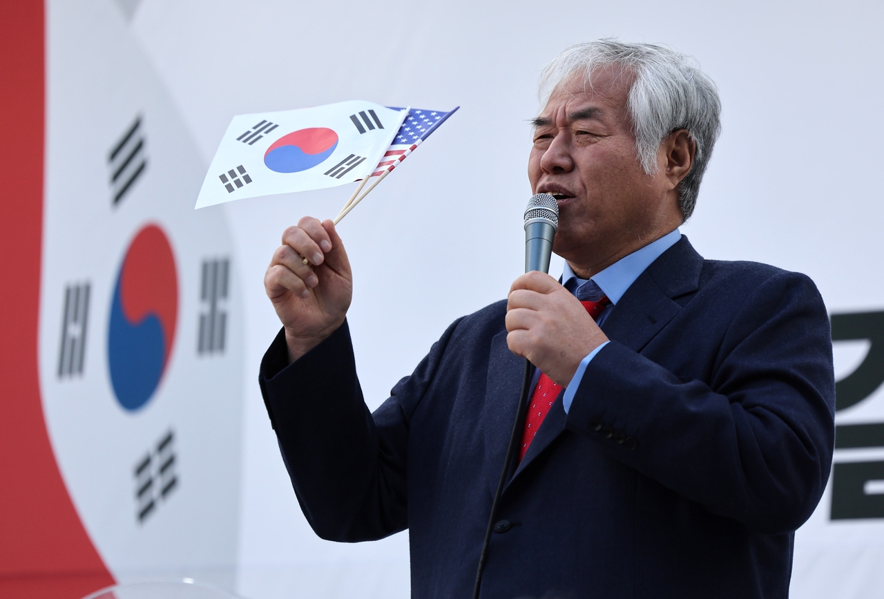 Holding South Korean and US flags, Protestant pastor Jeon Kwang-hoon addresses a crowd in Daegu on Feb. 18, advocating mass civil resistance on March 1 to overturn President Yoon Suk Yeol’s impeachment. (Newsis)