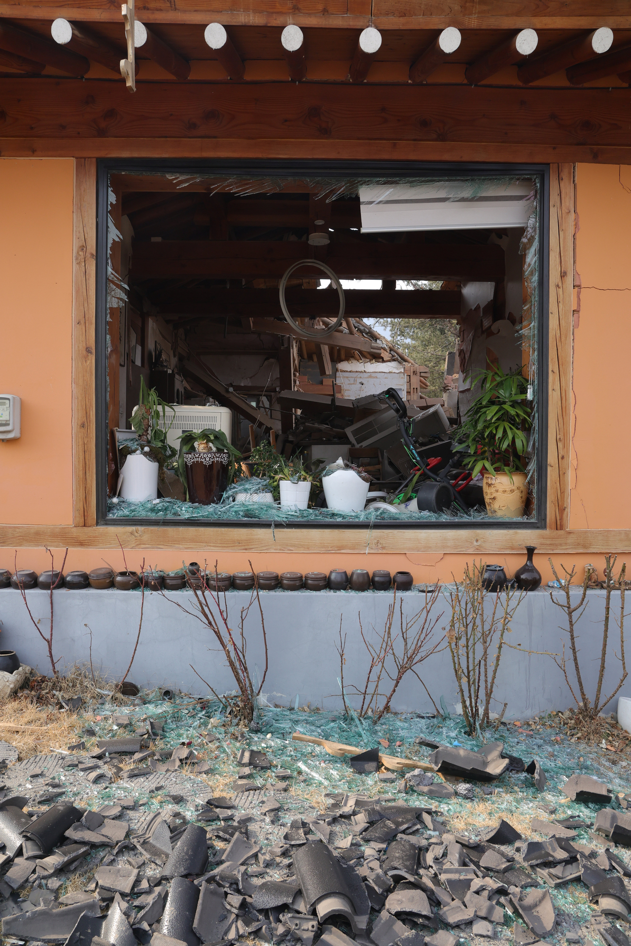 Glass from a shattered window lies infront of a damaged home. (Yonhap)