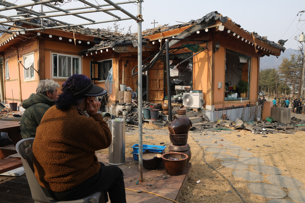 Residents on Friday look at their damaged home, which was destroyed after a fighter jet accidentally dropped multiple bombs in Pocheon, Gyeonggi Province, on Thursday. (Yonhap)