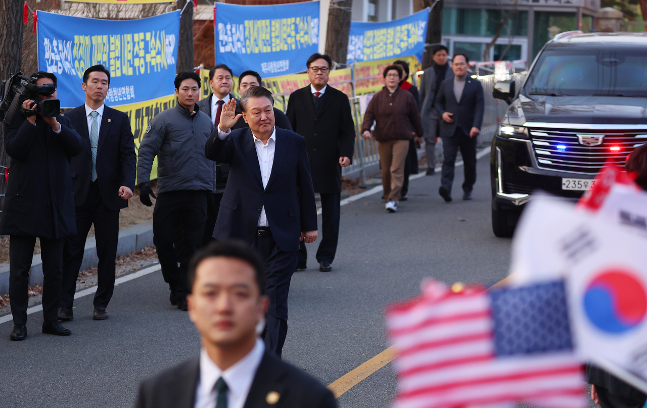 President Yoon Suk Yeol steps out of his security vehicle and greets supporters as he walks outside Seoul Detention Center in Uiwang, Gyeonggi Province, on Saturday before heading to his presidential residence in Hannam-dong, Seoul. (Yonhap)