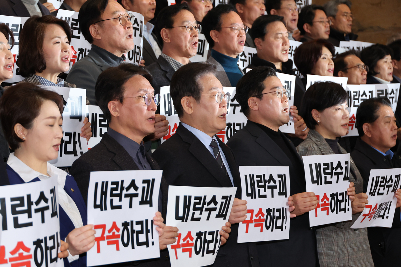 Lawmakers of South Korea's main opposition Democratic Party of Korea, including Chair Rep. Lee Jae-myung (front, third from left), hold signs saying, "Arrest the insurrection leader!" at the main building of the National Assembly on Sunday, a day after suspended President Yoon Suk Yeol was released from jail. (Yonhap)