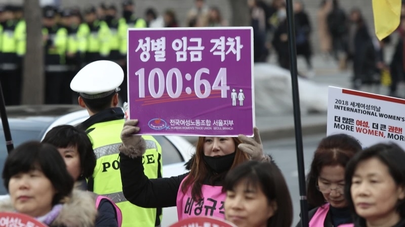 A Korean Women's Trade Union protester holds a sign highlighting South Korea's gender wage gap at an International Women's Day rally in Seoul on March 8, 2018. A 2020 Ministry of Gender Equality and Family survey showed women at 2,149 listed firms and 369 public institutions earned 35.9 percent less than men, receiving just 641,000 won per 1 million won earned by men. (Workers' Solidarity)