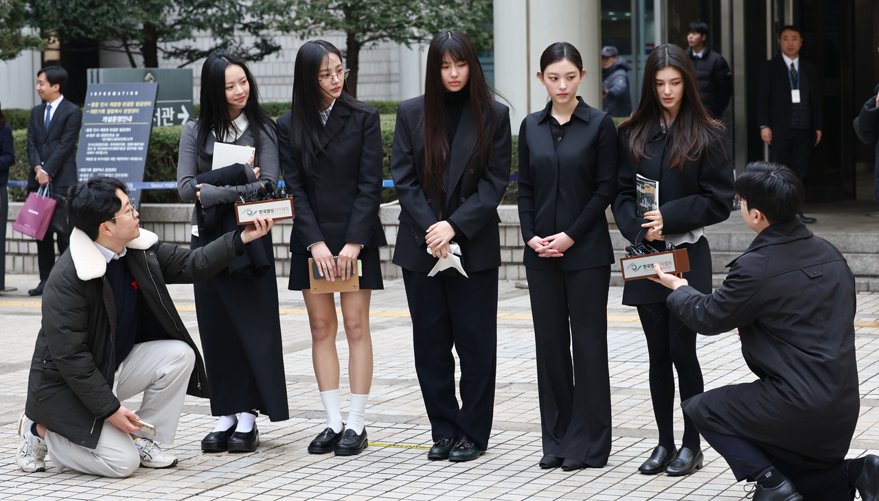 NewJeans members respond to reporters' questions as they leave the Seoul Central District Court, Friday. (Yonhap)
