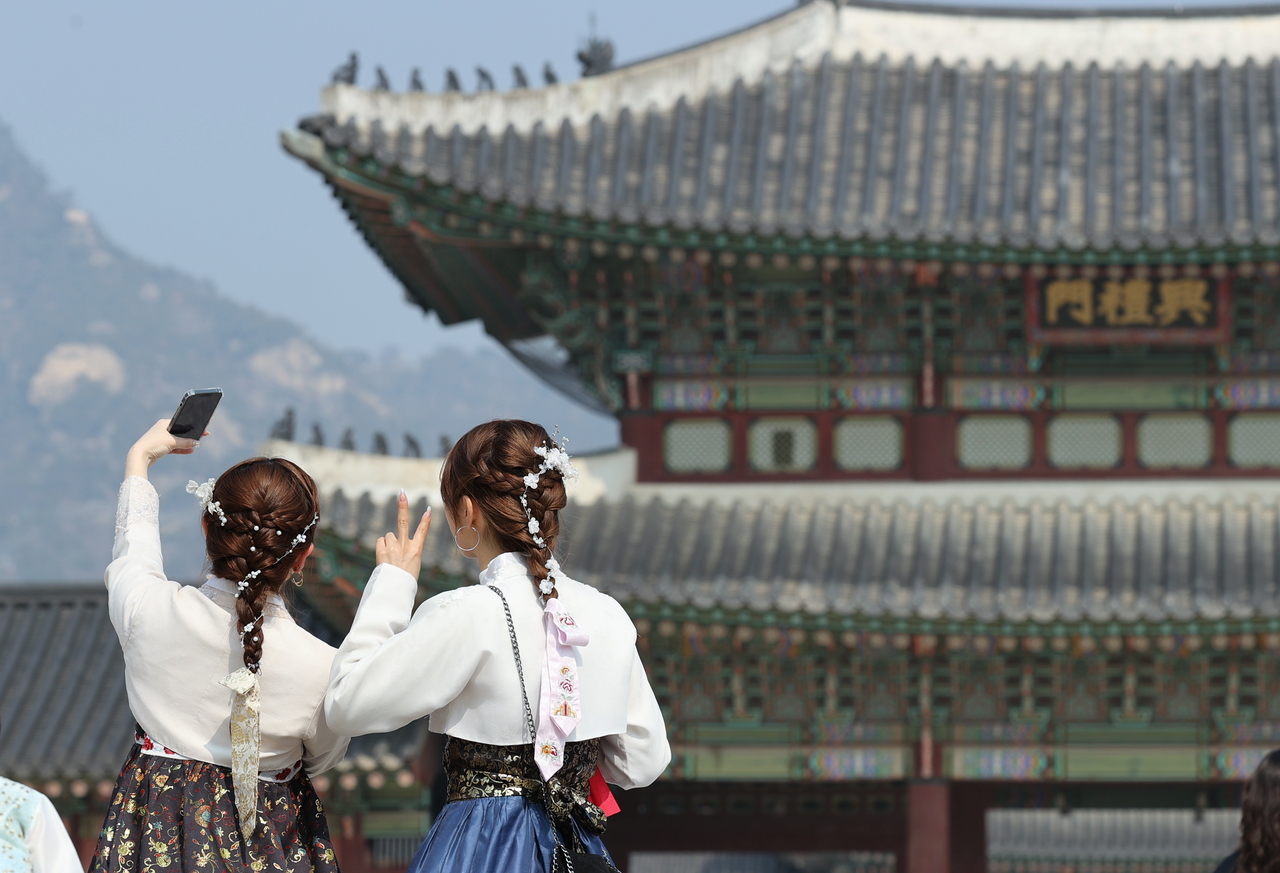 Tourists clad in hanbok take photos at Gyeongbokgung in Seoul on Monday. The city government said foreign tourism in Seoul in January fully recovered to the prepandemic level and set a new January record. (Yonhap)