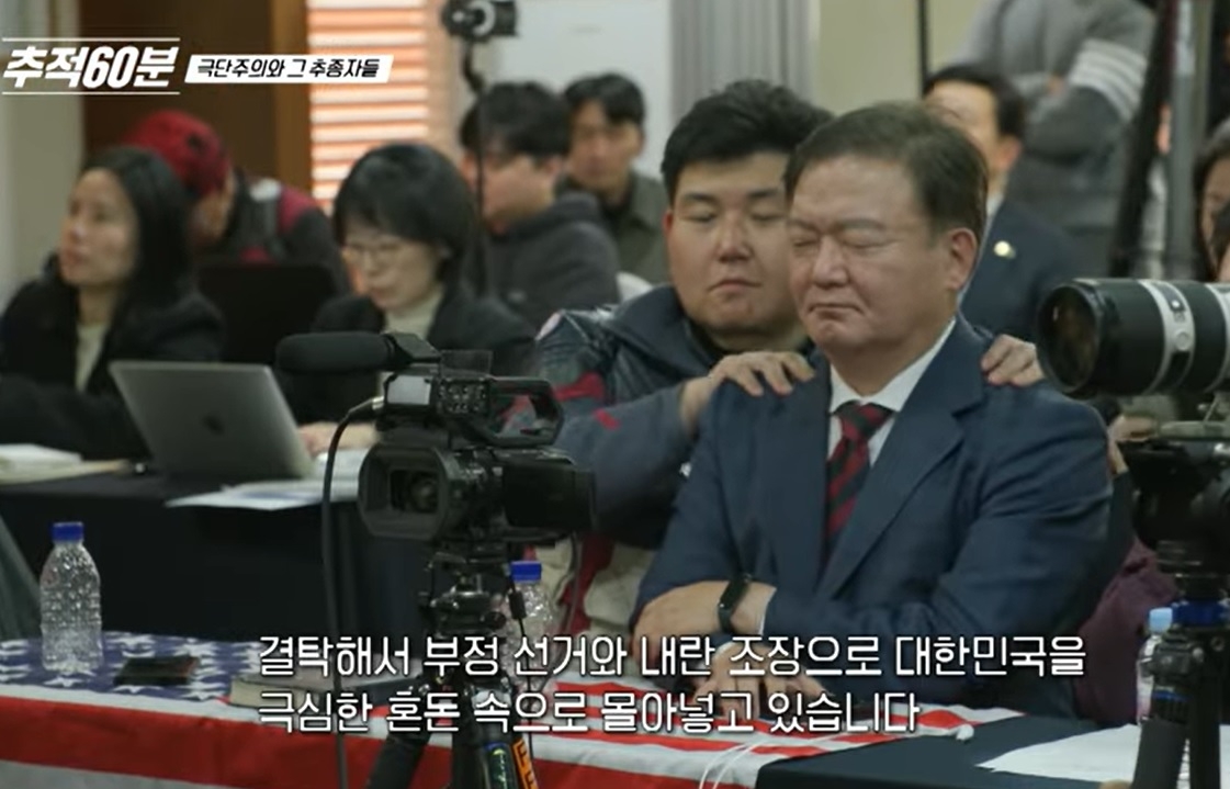 ‘선관위 중국인 간첩설’에 관한 제보를 했다고 주장하는 안병희 씨가 캡틴 아메리카 복장을 하고 민경욱 전 국민의힘 의원의 어깨를 주무르고 있다. [KBS추적60분]