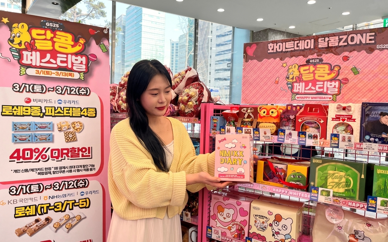 GS25 화이트데이 행사 존에서 모델이 NMIXX 굿즈 세트를 들고 포즈를 취하고 있다. [GS리테일 제공]