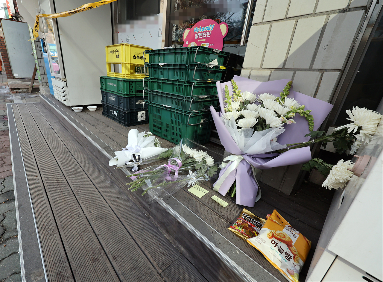 지난달 12일 30대 남성이 아르바이트생에게 흉기를 휘두른 사건이 벌어진 경기 시흥시의 한 편의점 앞에 추모의 글귀가 적힌 쪽지와 국화 꽃다발, 간식 등이 놓여있다. 2025.02.14 [연합]