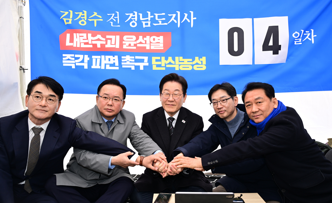 박용진 전 의원(왼쪽부터), 김부겸 전 국무총리, 이재명 더불어민주당 대표, 김경수 전 경남지사, 이광재 전 국회 사무총장이 12일 서울 광화문 인근 천막에서 윤석열 대통령 파면을 촉구하며 단식 농성에 돌입한 김경수 전 경남지사를 응원하며 손을 모으고 있다. [연합]