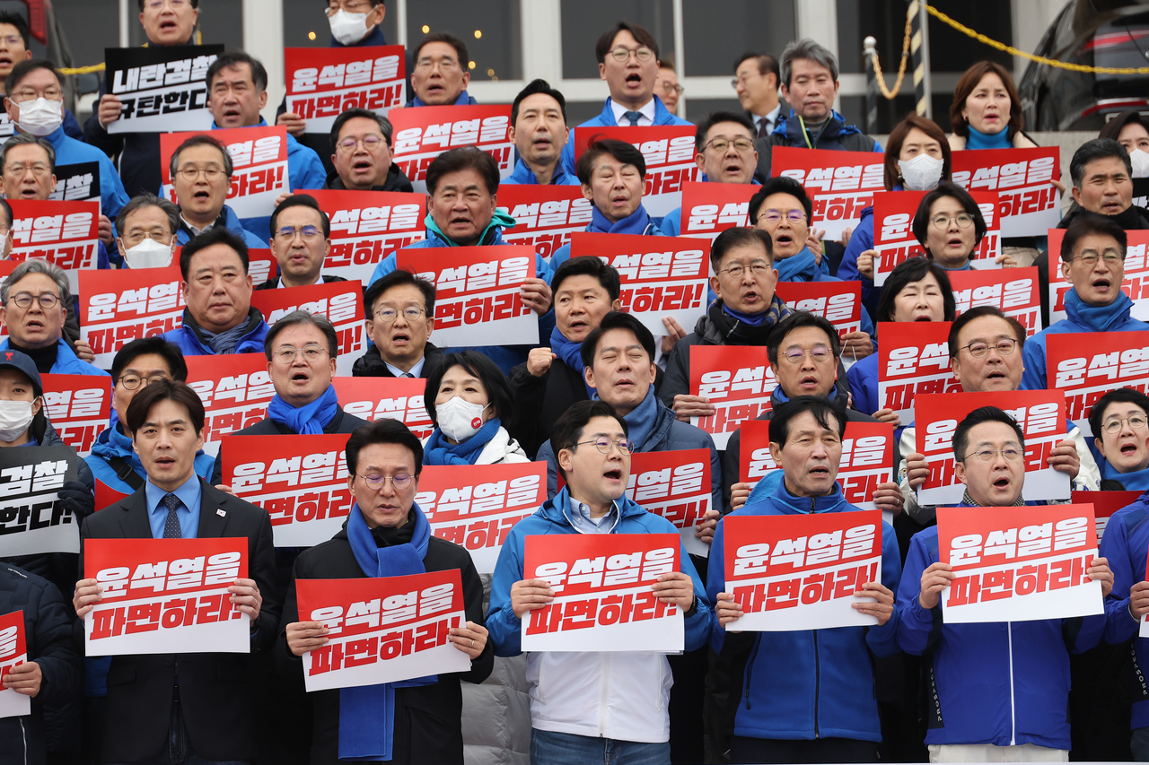 Democratic Party of Korea lawmakers hold signs that read "Fire Yoon" as they begin a march calling for the suspended president's impeachment on Wednesday. Yonhap